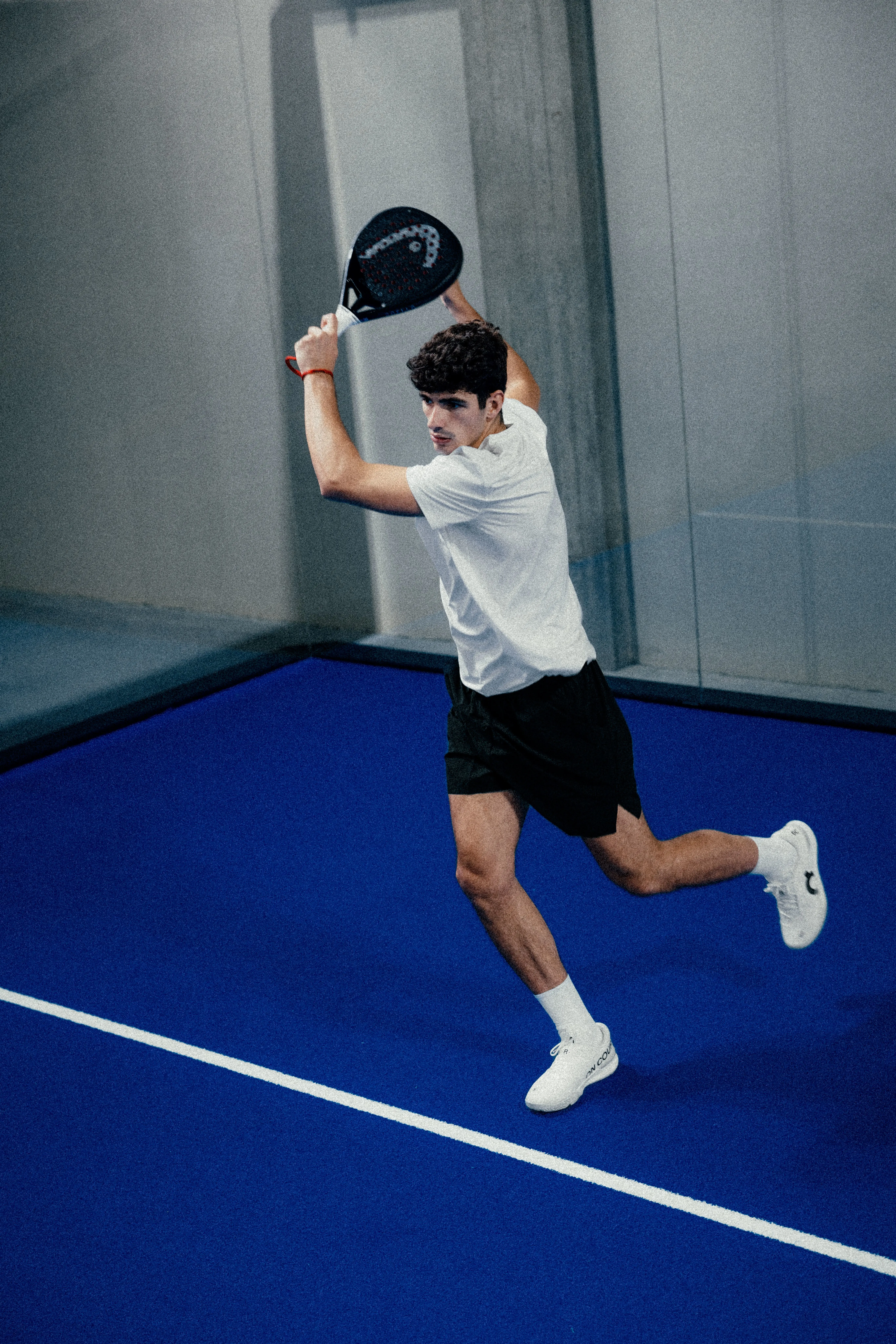 Un joueur de padel en tenue équipé de vêtements On, prêt à servir.