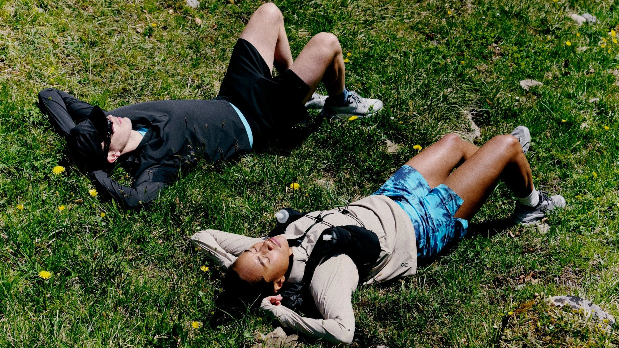 Deux runners allongés dans un champ, les yeux fermés. 