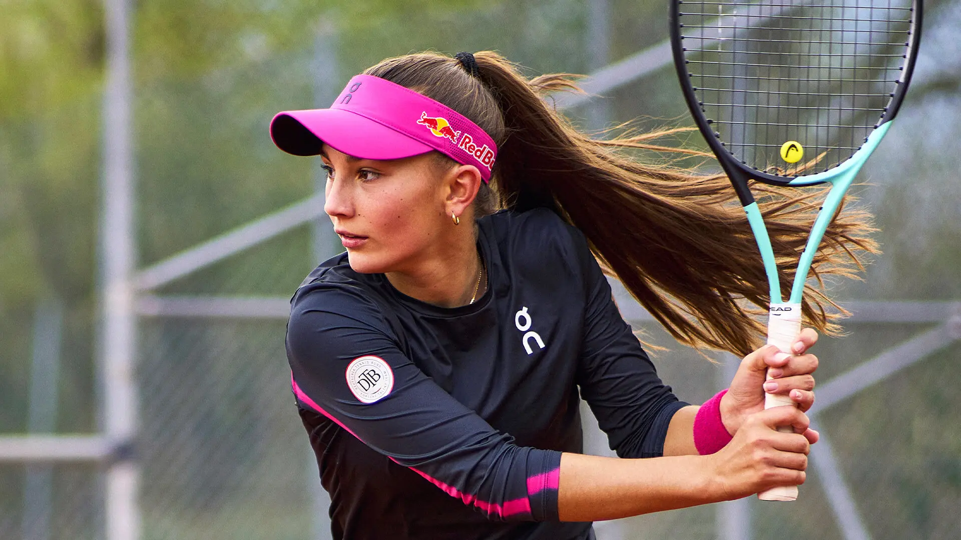 Julia Stusek, une visière rose sur la tête, s’apprête à renvoyer la balle de tennis. 
