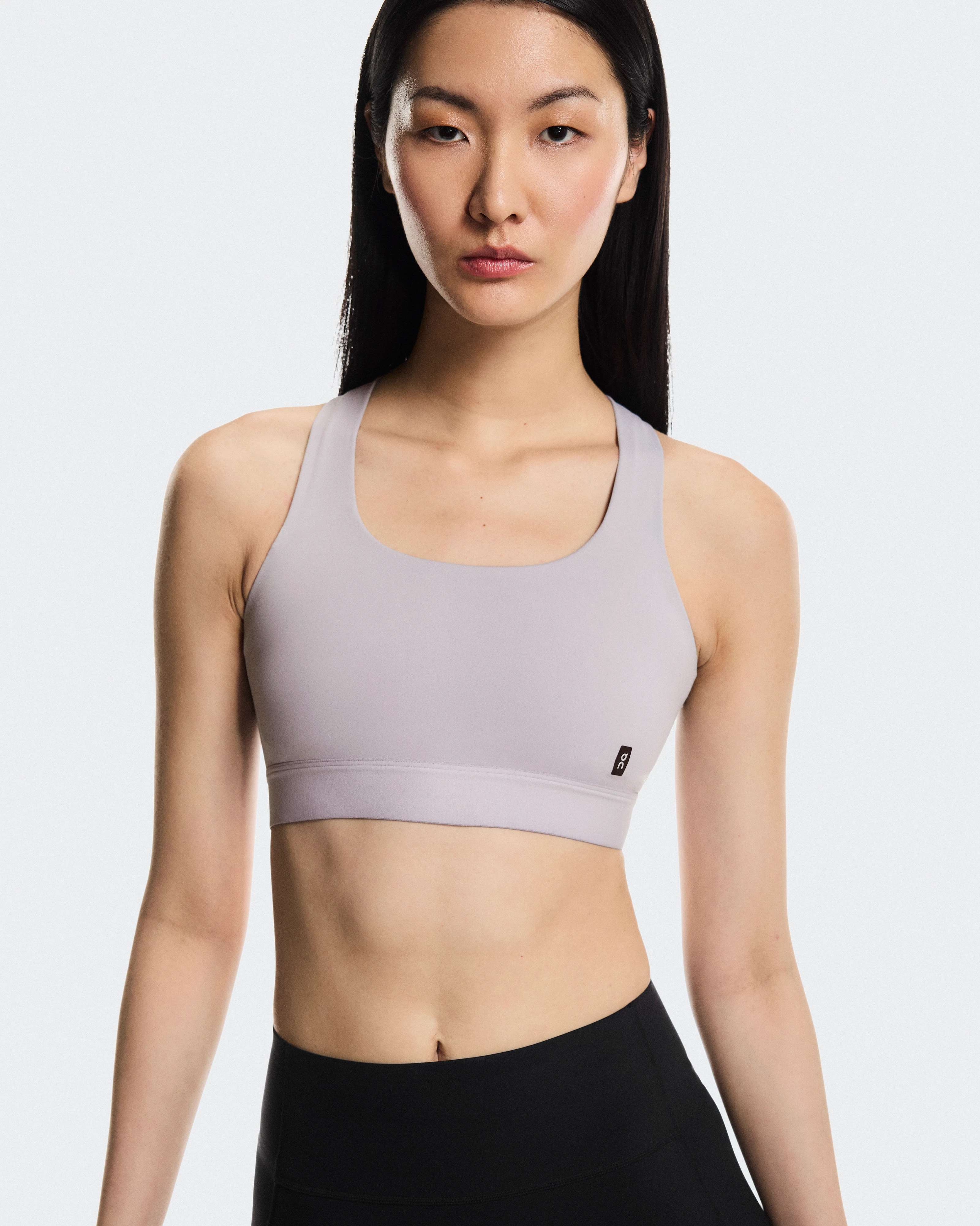 Une femme qui porte un soutien-gorge de sport et un legging On et regarde tout droit dans l’appareil, l’air sérieux.