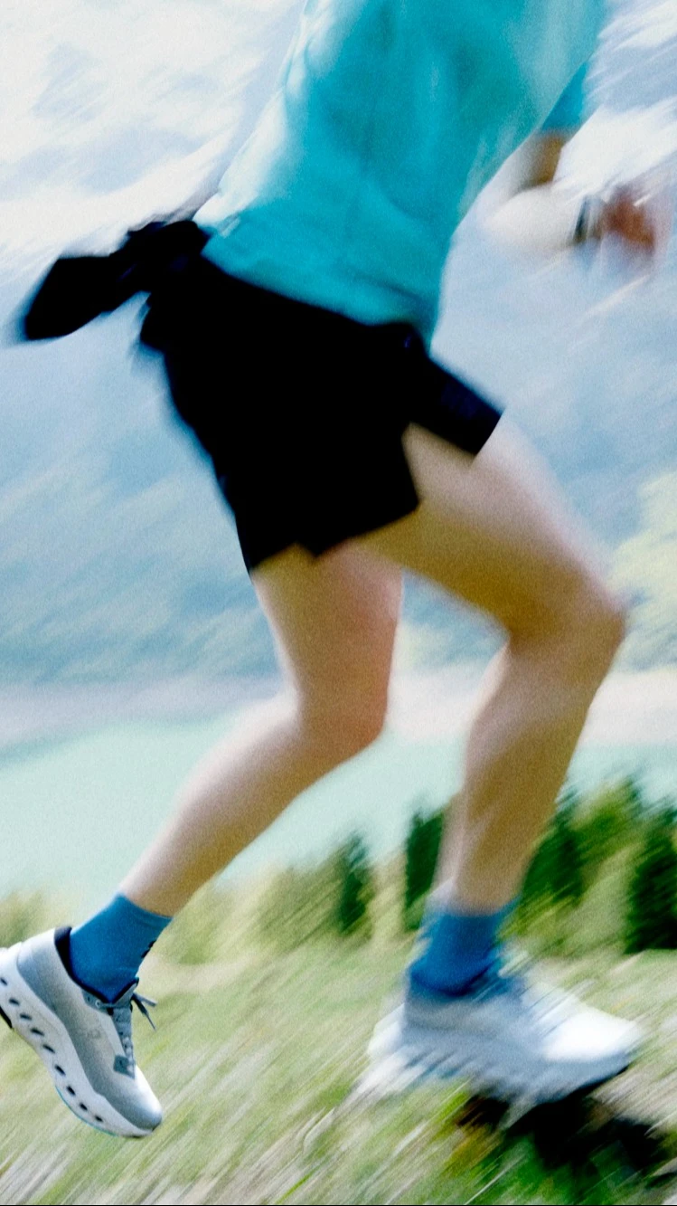 Image floue d’un runner sur un sentier de montagne.