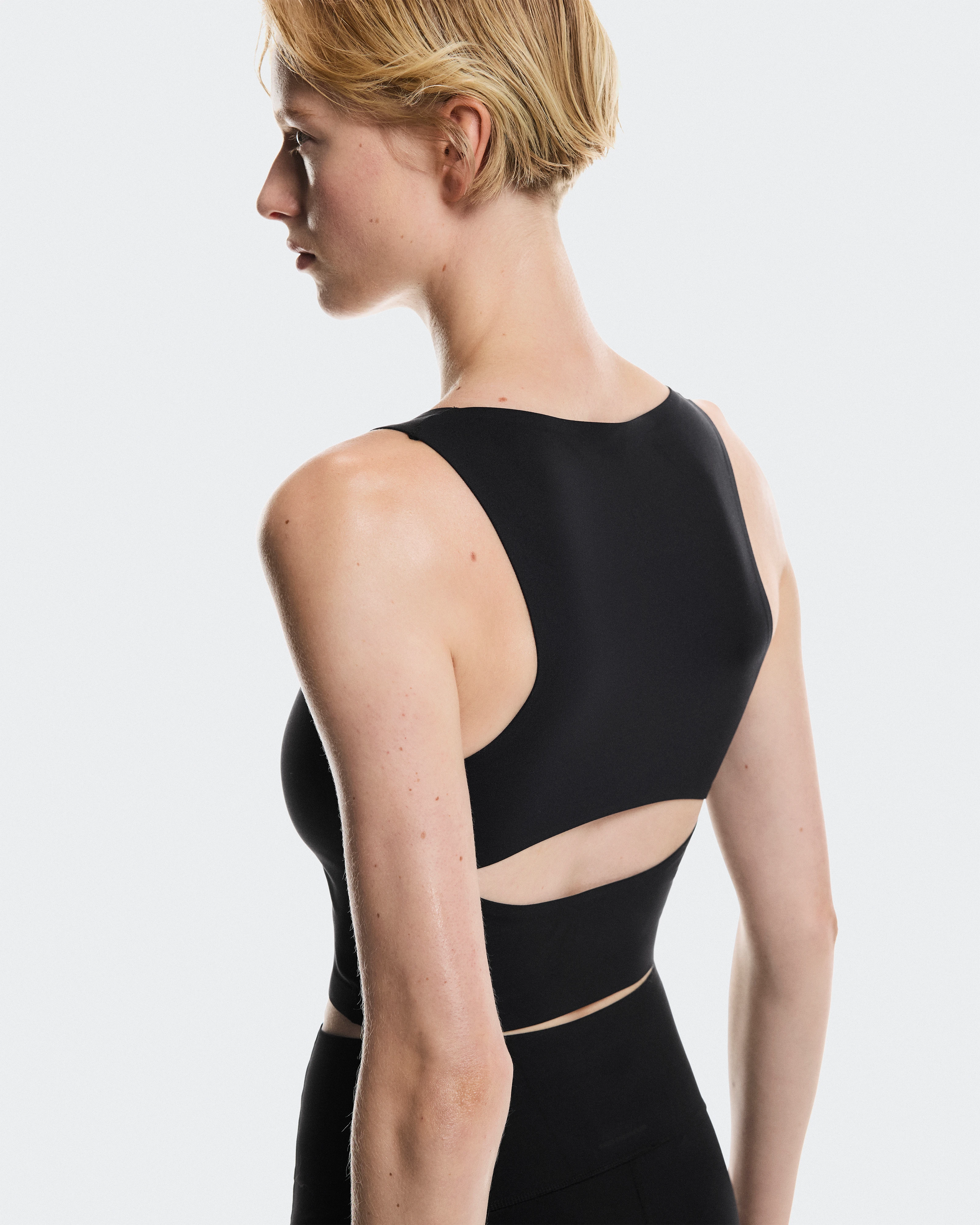 Profil d'une athlète vêtue de noir, avec une tenue noire On performante, qui regarde au loin.