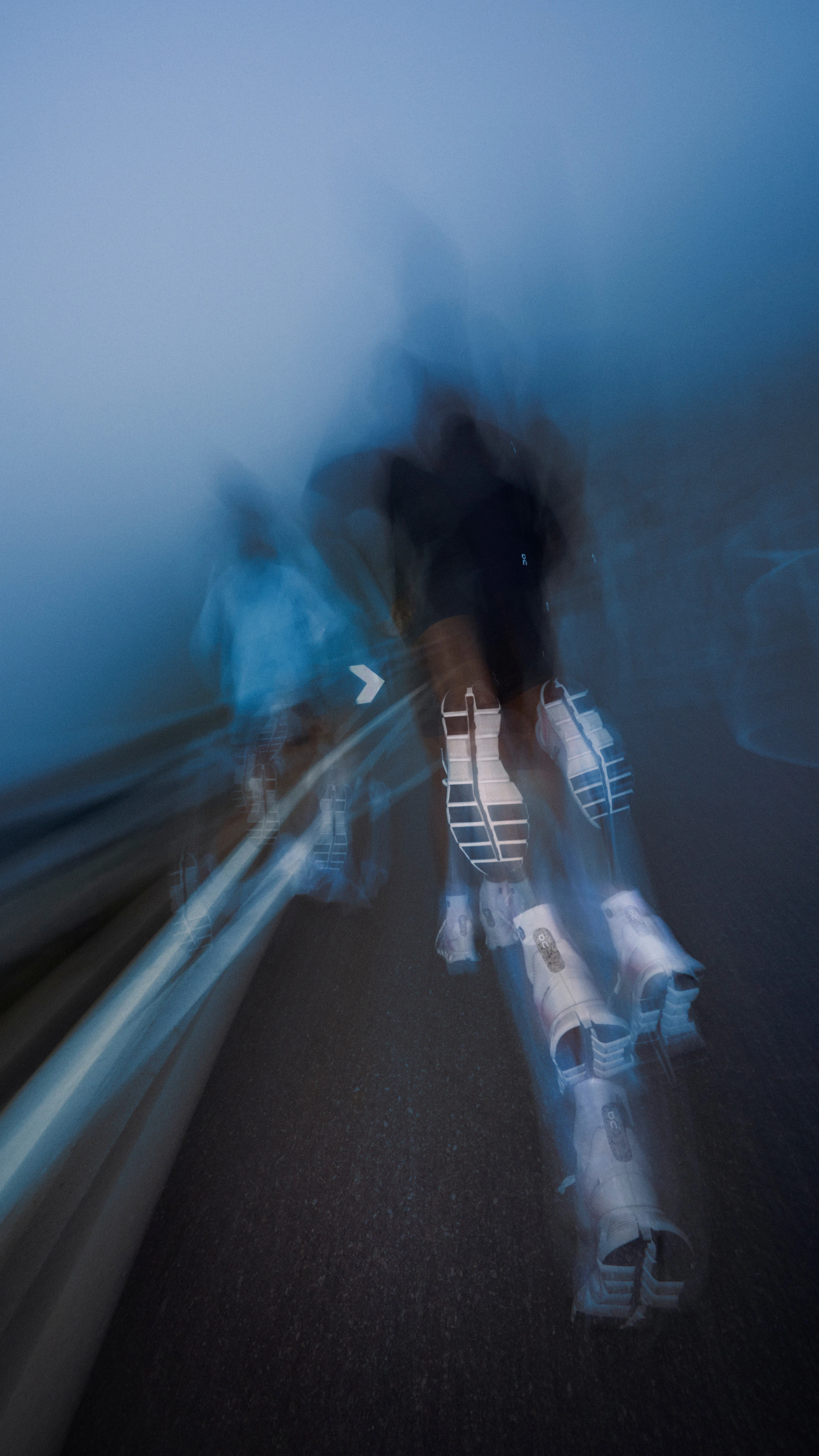 Deux personnes en train de courir dans la rue sur de l’asphalte mouillé. Un effet flouté suggère qu’elles se déplacent rapidement.