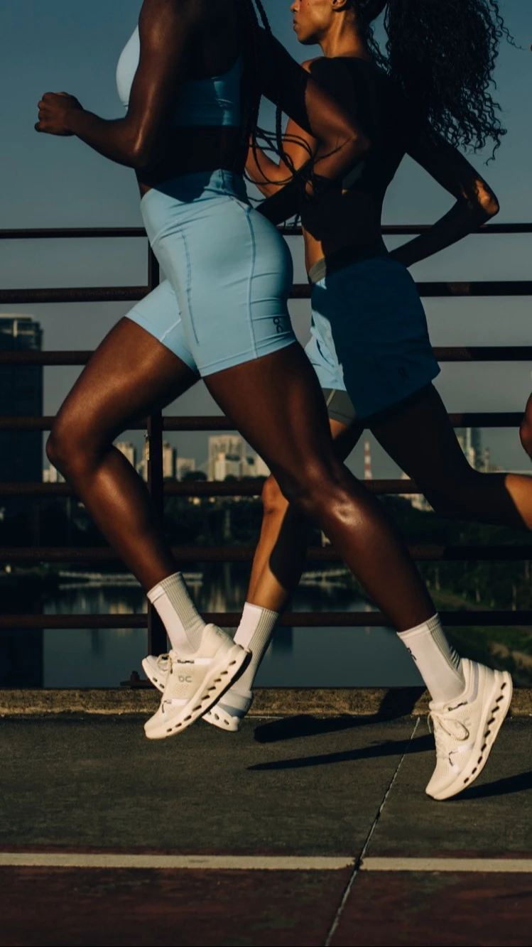 Trois runners traversant un pont en ville, avec leurs têtes hors champ.