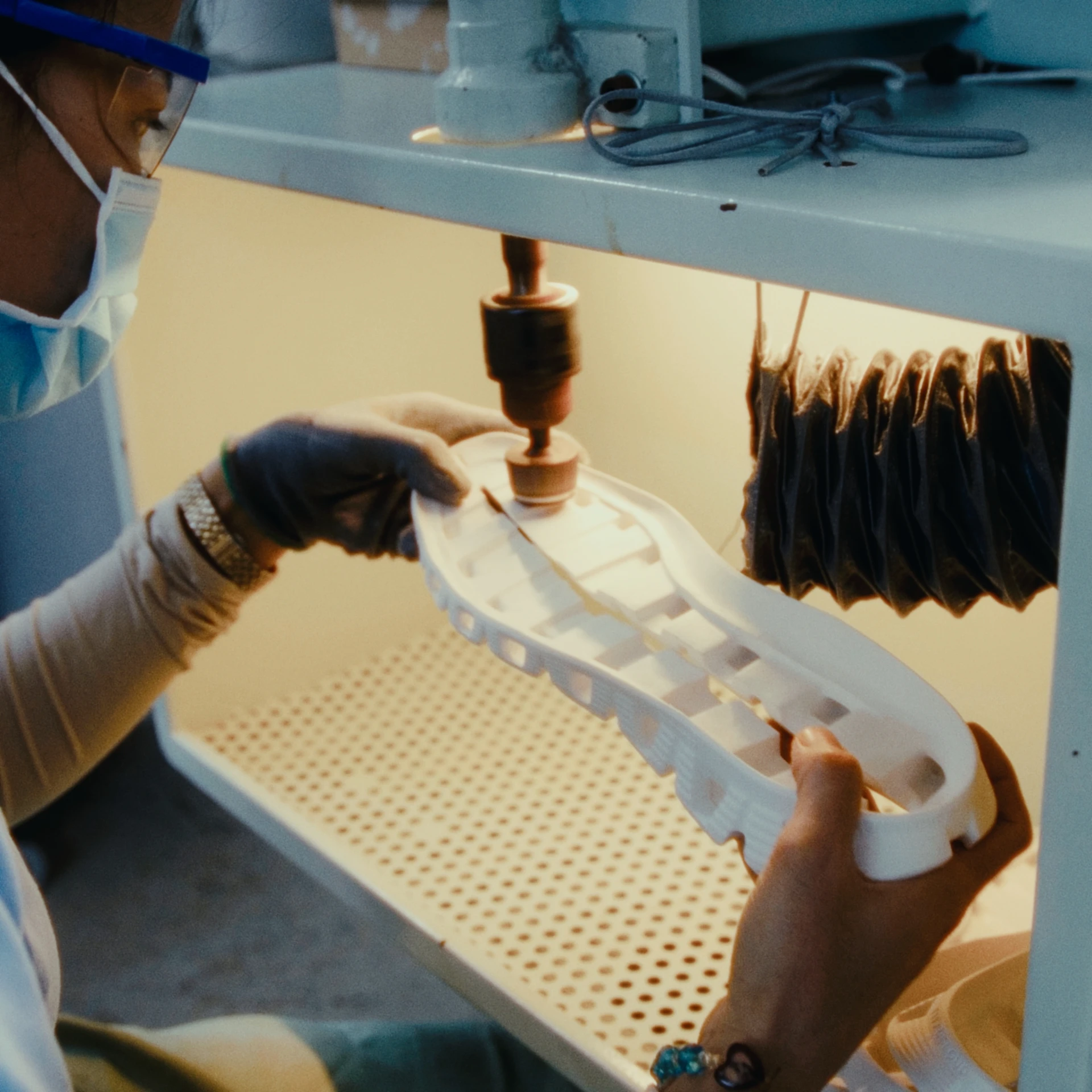 Technicienne de laboratoire travaillant avec une machine sur la semelle extérieure Cloudprime, portant des gants et des lunettes.