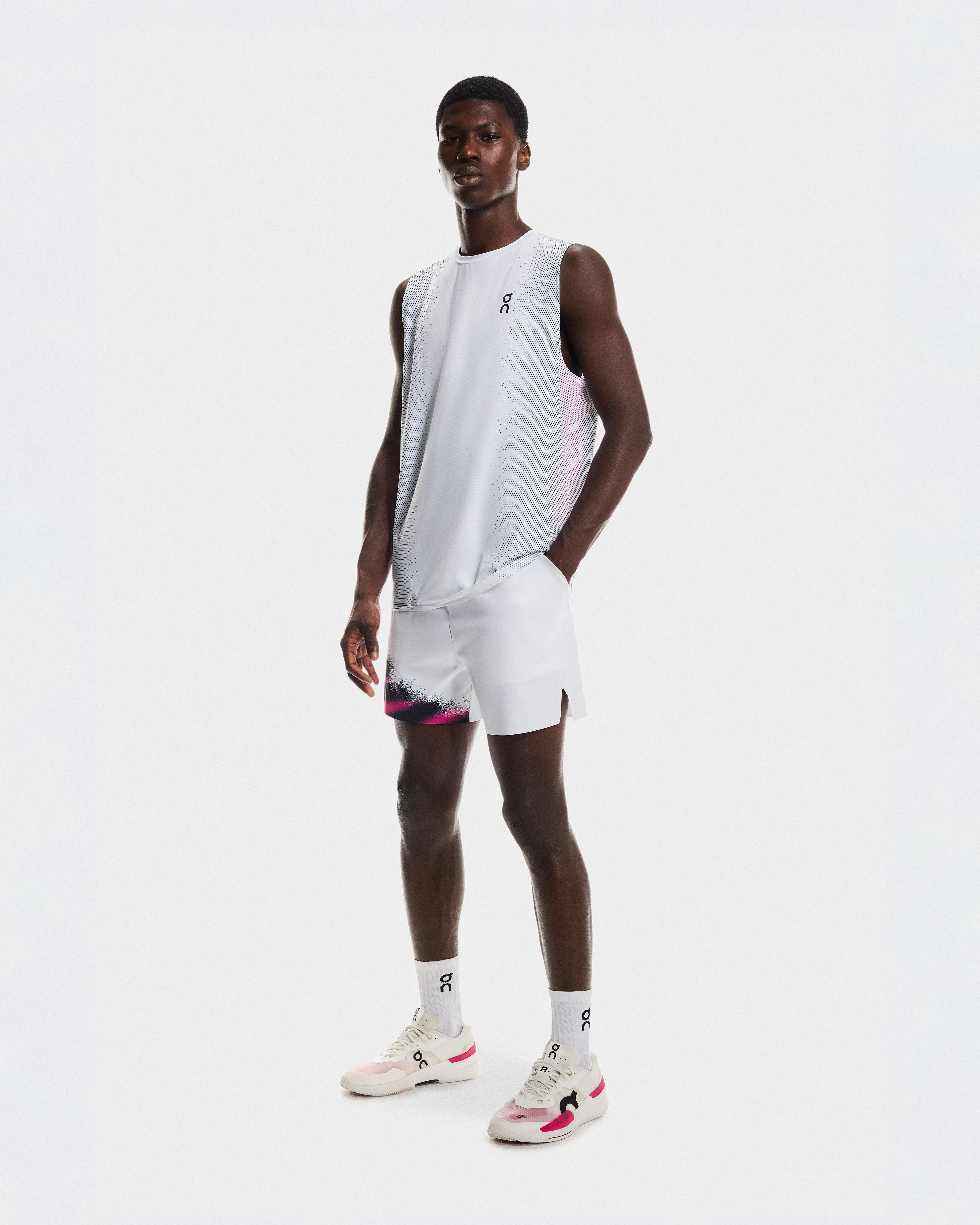Un athlète posant en équipement de performance blanc On, y compris short, débardeur et chaussures de training.