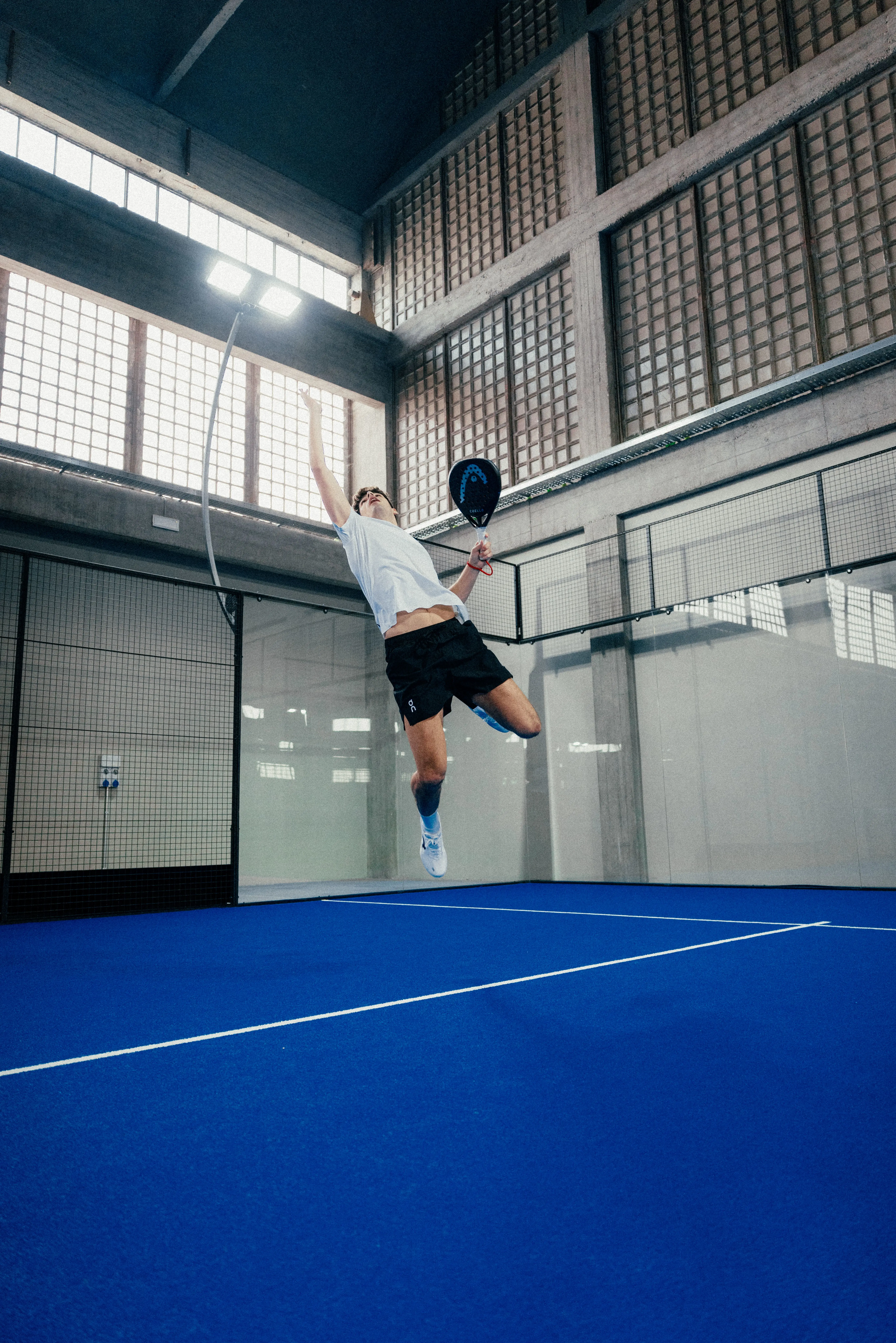 Un joueur de padel en plein saut, le corps entièrement déployé.