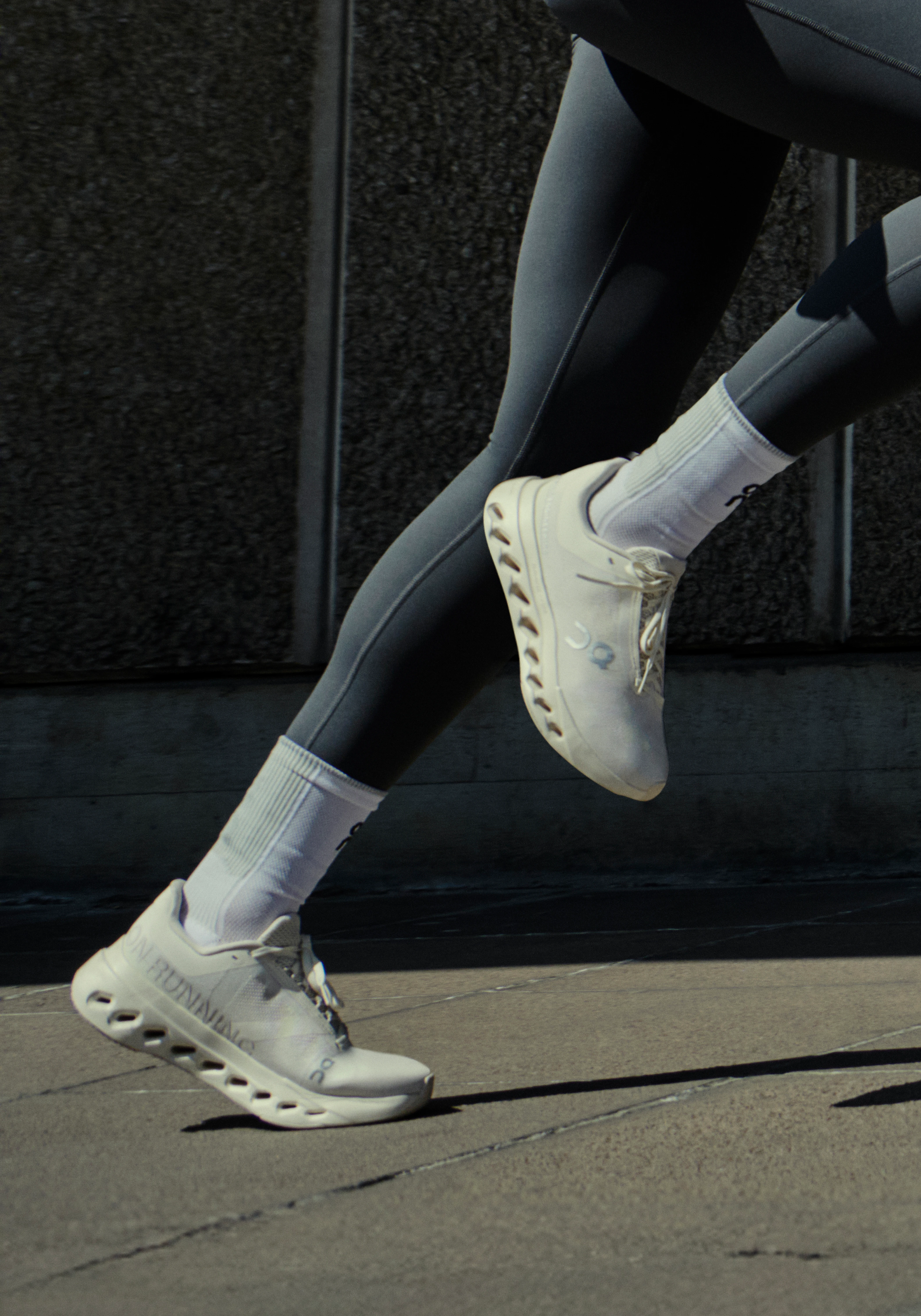 Gros plan des jambes d’une athlète en chaussures et legging On à mi-foulée sur le trottoir.
