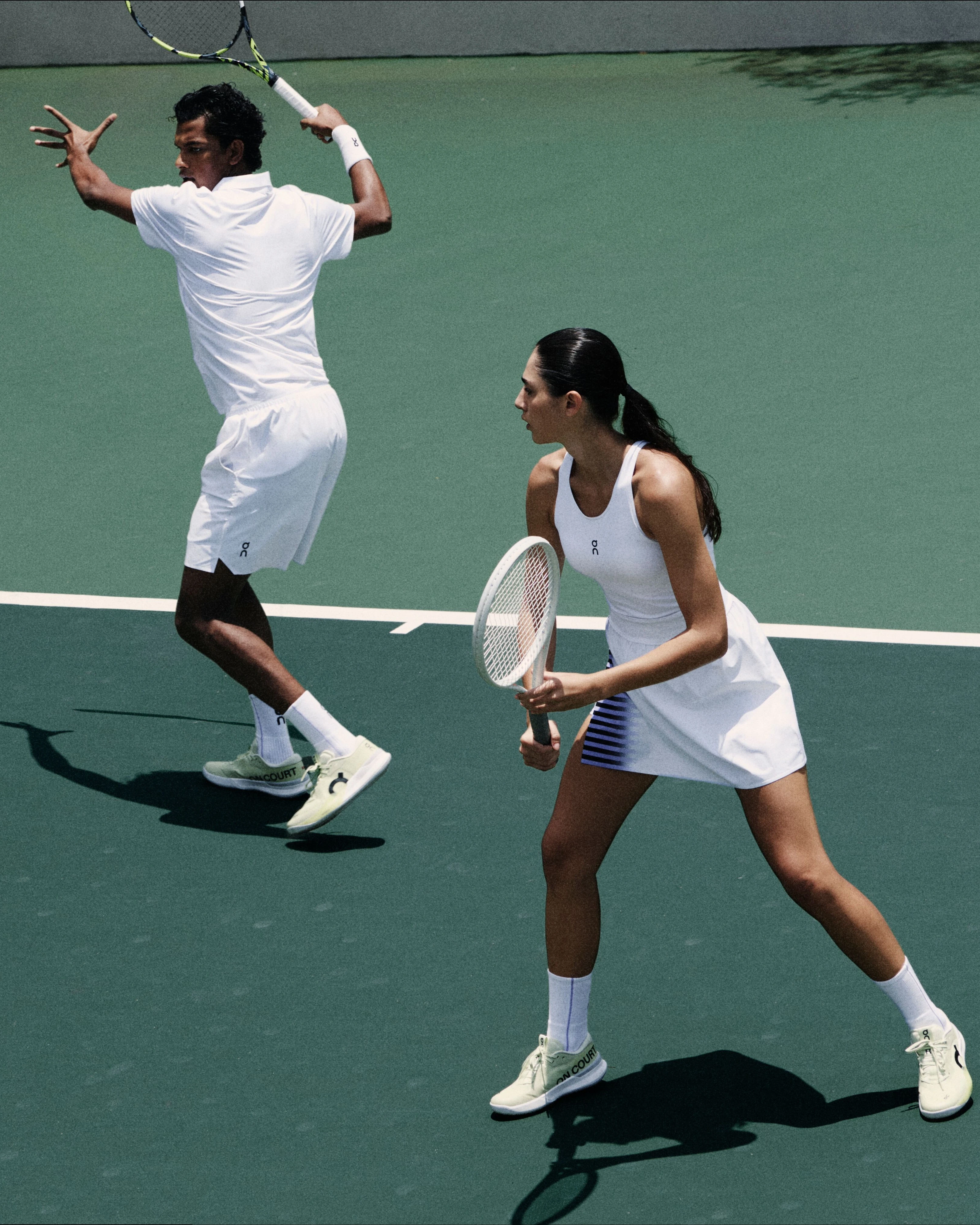 Joueur·ses de tennis en tenue blanche On, en plein mouvement de frappe.