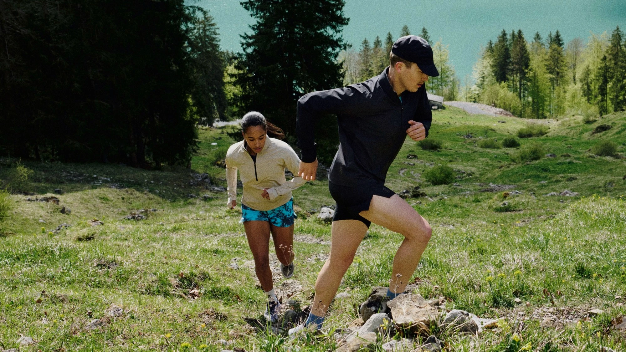 Deux runners gravissant une montagne herbeuse.