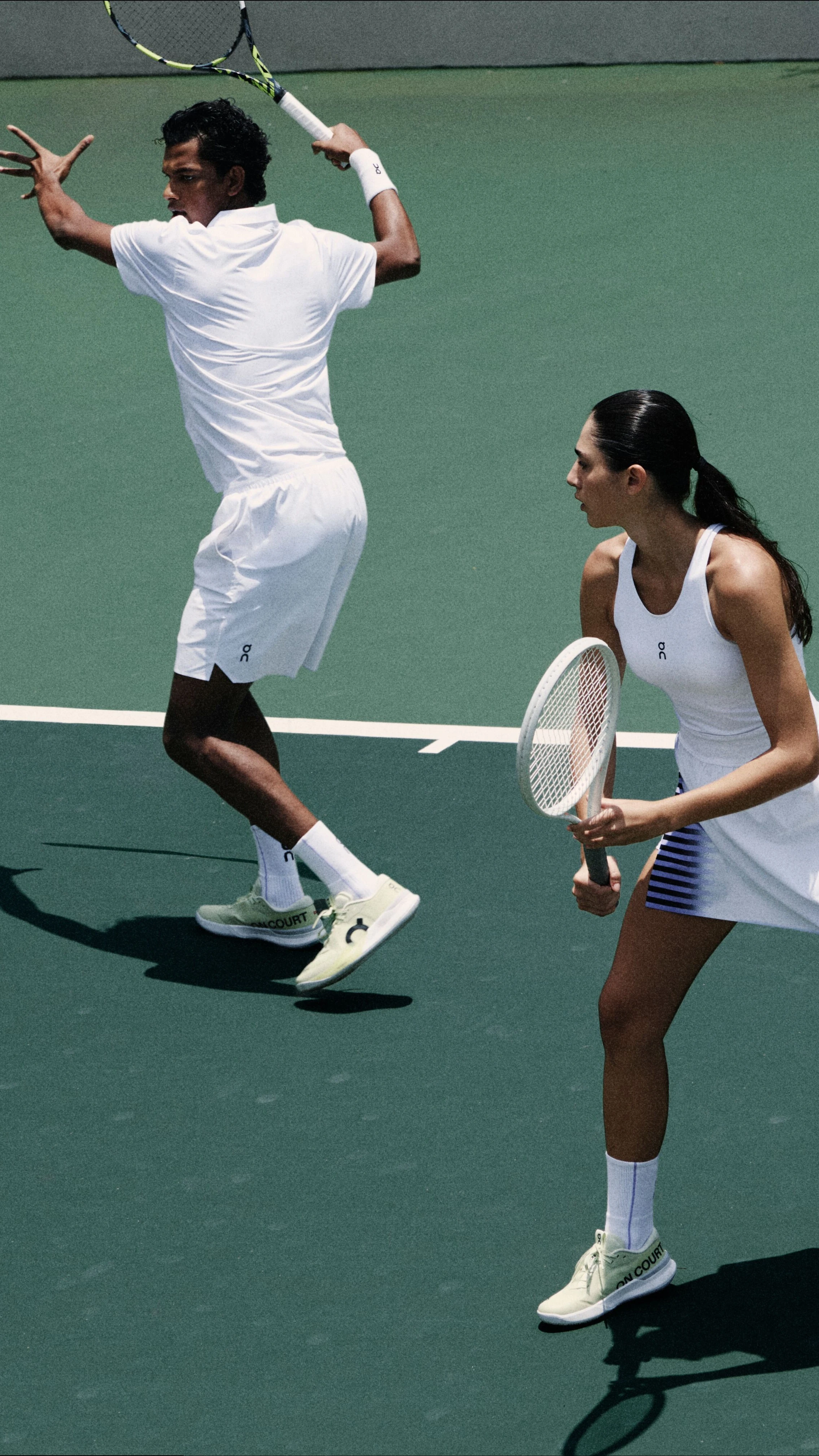 Joueur·ses de tennis en tenue blanche On, en plein mouvement de frappe.