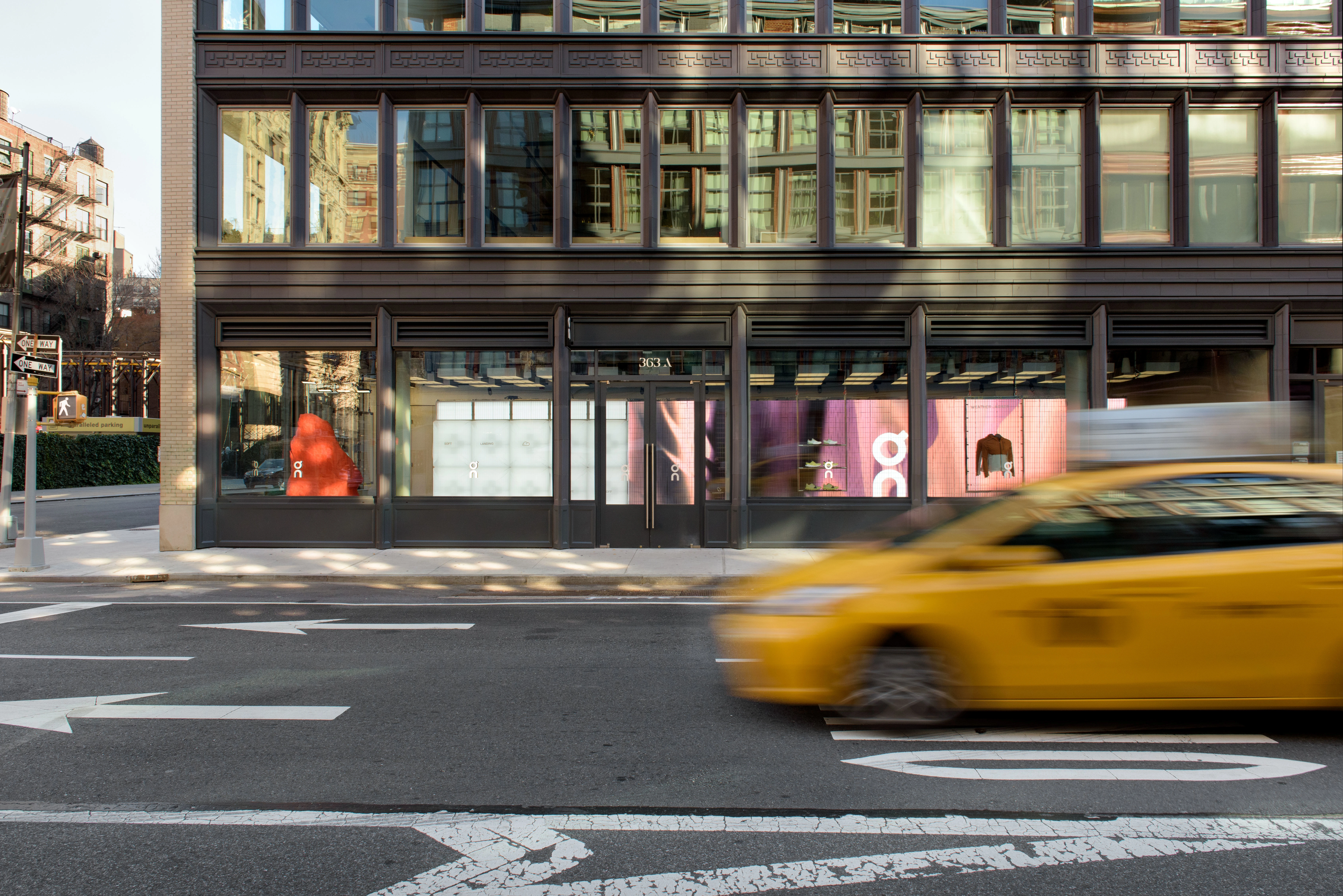 Extérieur de la boutique On à New York, avec un taxi jaune flou au premier plan.