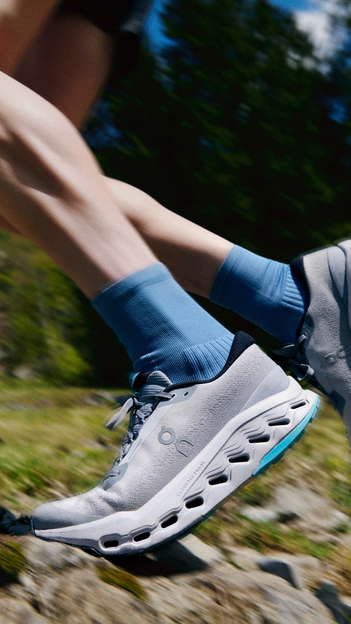 Gros plan sur des chaussures de running On sur un sentier de montagne.
