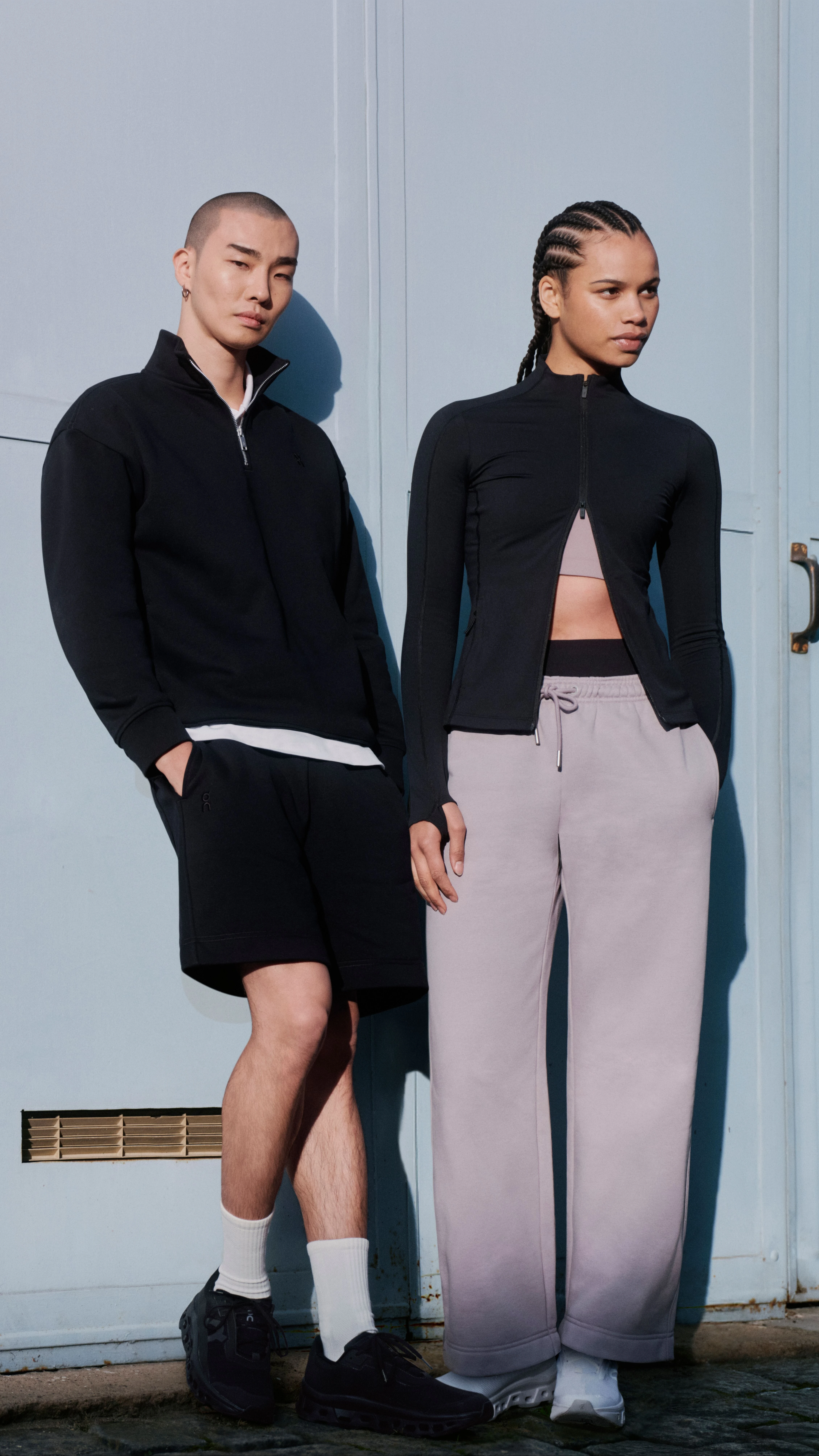 Deux personnes en tenue streetwear On, adossées à un mur.