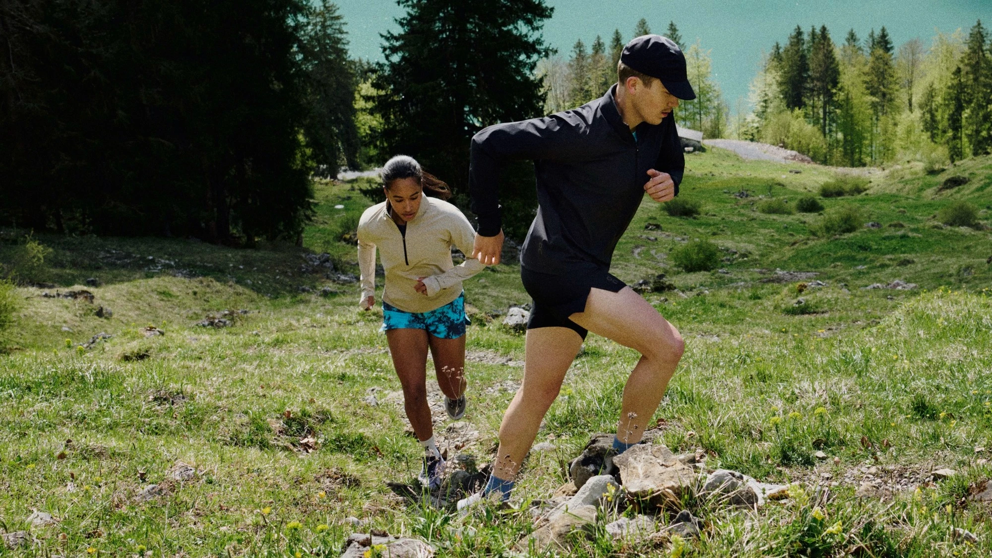 Deux runners gravissant une colline avec un lac en arrière-plan.