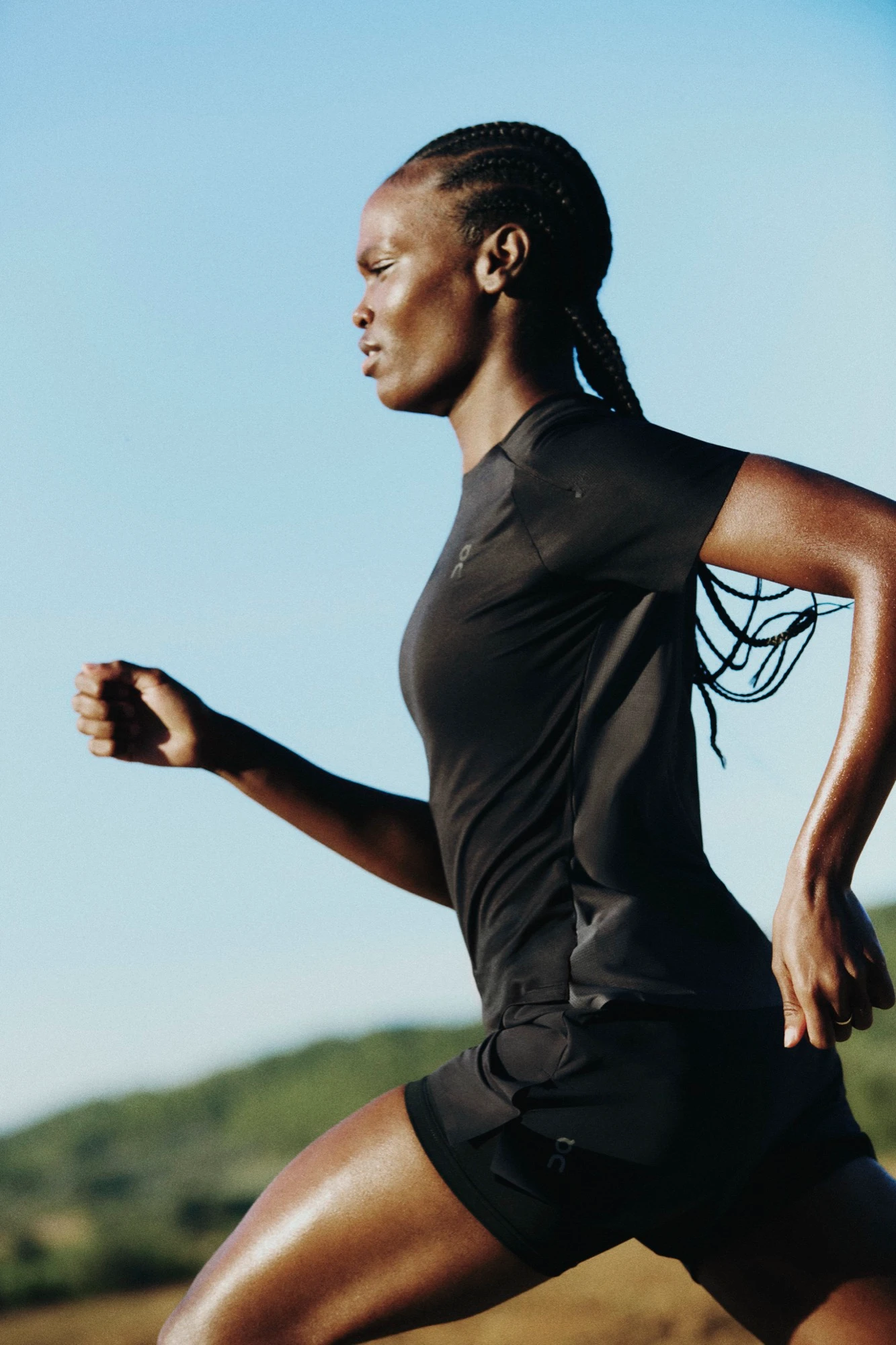 Un runner habillé de noir faisant un jogging sous un ciel bleu éclatant.