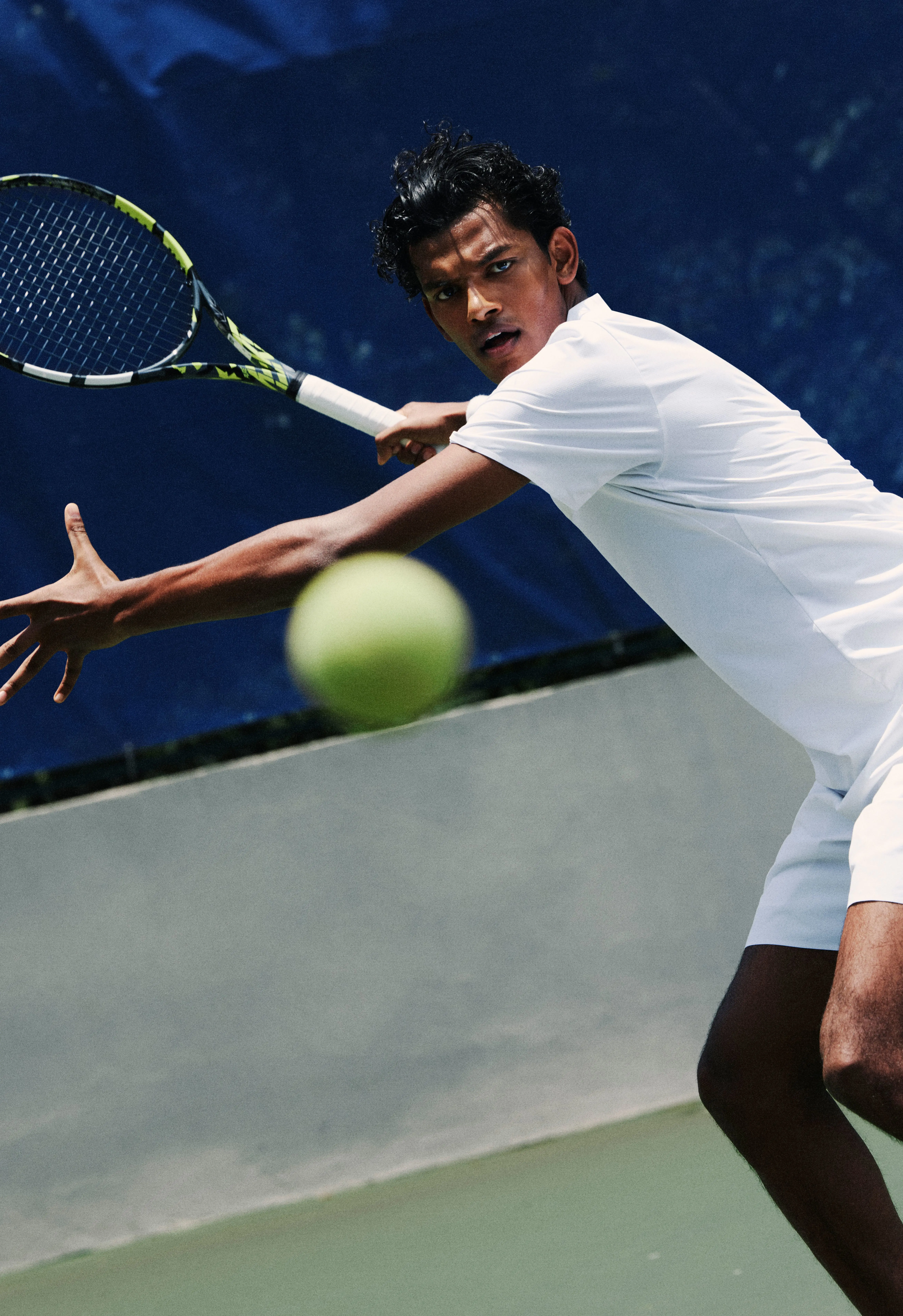 Une joueuse de tennis prête à frapper la balle, celle-ci étant au premier plan.