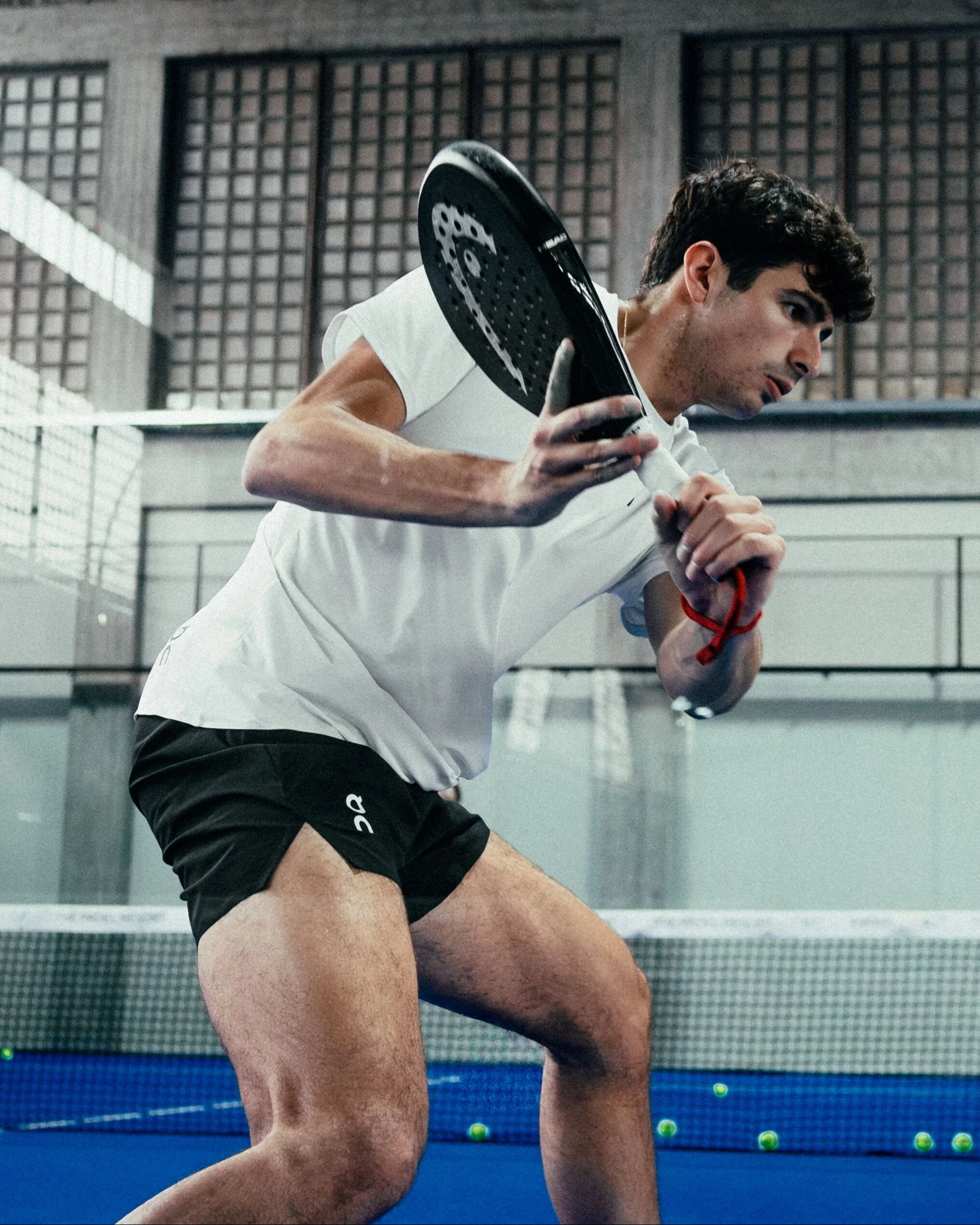 Un joueur de padel équipé de vêtements On frappe la balle avec sa raquette.